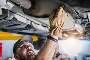 CloseupOfCarCatalyticConverterBeingCheckedByProfessionalMechanic - Meineke Indiana Solvex Auto Meineke Car Care | Noblesville IN | Catalytic Converter